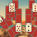 Cartas de juego dispuestas en pilas desiguales sobre un fondo de una ciudad con paisajes montañosos al atardecer