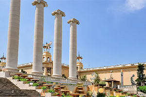 Columnas altas y blancas frente a una estructura con decoración clásica y cielo azul de fondo