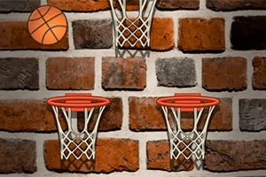 Tres aros de baloncesto en una pared de ladrillo con un balón de baloncesto en la esquina superior izquierda