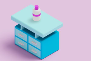 Mesa azul con cajones y una botella blanca con tapa morada sobre un fondo rosa