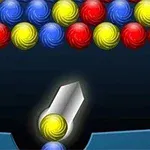 Bolas de colores rojas, azules y amarillas en un patrón sobre un fondo oscuro con un lanzador central