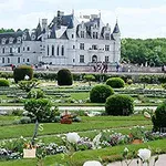Un castillo imponente en el fondo con jardines bien cuidados y flores en primer plano