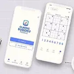 Dos teléfonos inteligentes con una aplicación de rompecabezas en pantalla, rodeados de una planta, un reloj blanco, lápices y una libreta sobre un fondo claro