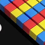 Pelota blanca acercándose a una pared de bloques de colores rojo, amarillo y azul sobre un fondo negro