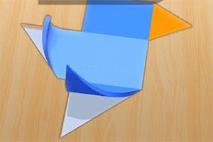 Figura de papel doblado en tonos azul, blanco y naranja sobre una superficie de madera