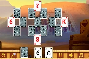 Cartas de juego de solitario dispuestas en un patrón sobre un fondo temático del Antiguo Egipto, con estatuas y un paisaje desértico