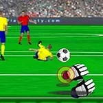 Jugador en uniforme amarillo intenta patear un balón hacia una portería mientras otro jugador está en movimiento y se ven guantes de portero en primer plano