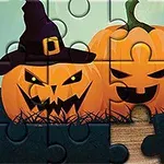 Dos calabazas de Halloween con caras espeluznantes y un sombrero de bruja en un rompecabezas parcialmente armado sobre una superficie de madera