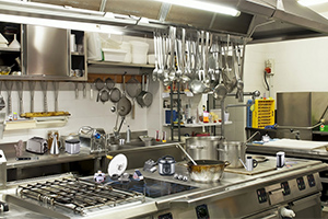 Cocina industrial con utensilios colgados, estufa de gas y equipamiento profesional
