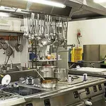 Cocina industrial con utensilios colgados, estufa de gas y equipamiento profesional