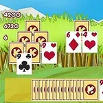 Cartas de juego dispersas sobre un fondo de pasto verde con montañas al fondo y una fila de cartas boca abajo al frente