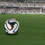 Balón de fútbol en un campo de juego con gradas y multitud de fondo