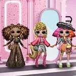 Cuatro muñecas con atuendos coloridos y extravagantes posan en un escenario rosado con espejos y luces brillantes