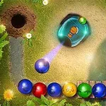 Bolas de colores en fila serpenteante cerca de un túnel, con un lanzador en el centro disparando una bola morada en un entorno de césped