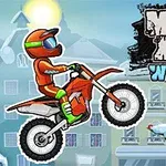 Motociclista con casco naranja y verde montando una moto en un paisaje invernal con un árbol decorado de fondo