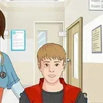 En un pasillo de hospital, una enfermera sonriente acompaña a un joven en una silla de ruedas