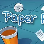 Texto Paper Flick en fondo azul con una bola de papel arrugada, hojas volando, un vaso naranja y un ventilador pequeño