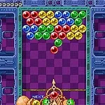 Burbujas de colores agrupadas en la parte superior de una pantalla con un fondo de tablero púrpura, mientras un lanzador dispara burbujas desde abajo