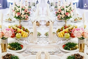 Mesa elegante decorada con arreglos florales y platos de frutas en un banquete