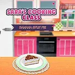 Mujer sonriente en una cocina colorida con un pastel de plátano en la mesa y un cartel que dice Saras Cooking Class: Banana Split Pie