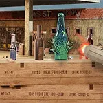Una mano sosteniendo una pistola dispara hacia botellas de vidrio sobre cajas de madera