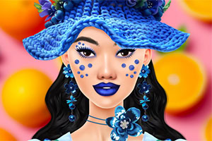 Mujer con maquillaje azul, usando un sombrero y accesorios florales del mismo color frente a un fondo de colores brillantes