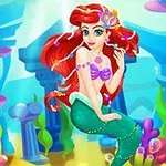 Una sirena pelirroja con cola verde y un top morado, rodeada de corales y antiguas ruinas submarinas